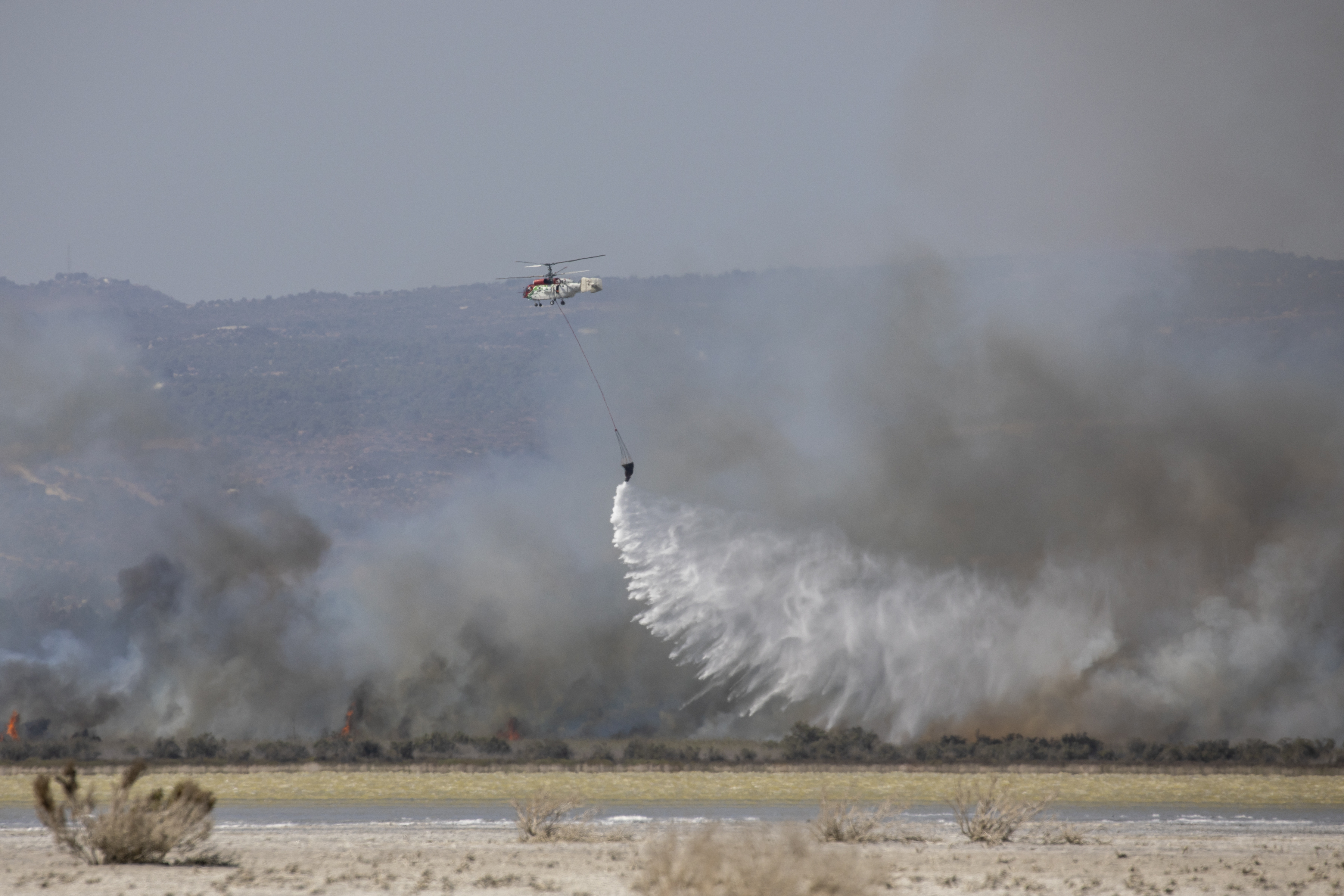 Image shows helicopter dropping water from under sling